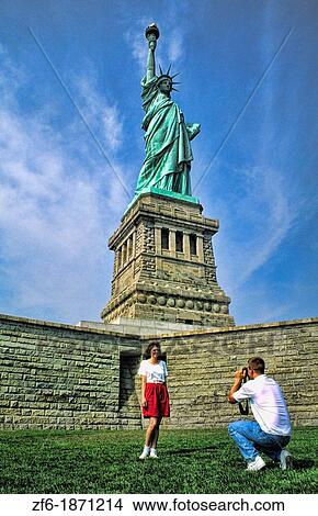 Picture - A couple of torists taking photos at the beauty of the famous Statue of Liberty on Ellis Island in New York City USA. Fotosearch