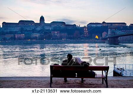 A couple rest in the shore of the Danube river, in front of the Royal Palace. View Large Photo Image Stock Image - A couple rest in the shore of the Danube river, in front of the Royal Palace.. Fotosearch