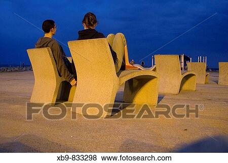 A couple sits on a Barcelona beach at twilight View Large Photo Image Stock Photo - A couple sits on a Barcelona beach at twilight. Fotosearch