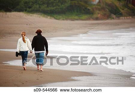Stock Photograph - A couple walk on Baker Beach in San Francisco, California, United States of America. Fotosearch
