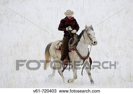 Stock Image - A cowboy out for a winter ride, Shell, Wyoming, Usa. Fotosearch