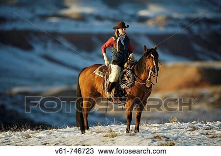 Stock Image - A cowgirl out for a ride in the snowy mountains of Shell, Wyoming, USA. Fotosearch