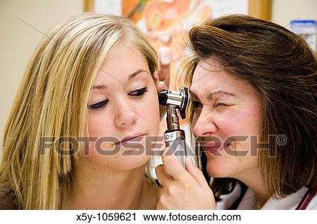 Stock Image - A doctor examining a teenage female patient with an ear scope. Fotosearch