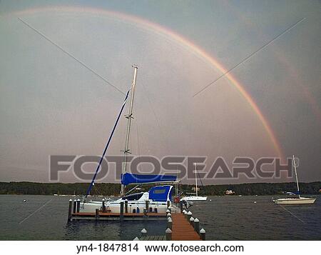 Picture - A double rainbow appears over Martha, s Vinyard, Massachusetts on a stormy day Boats are moored in Laguna Pond, an Atlantic Ocean inlet. Fotosearch