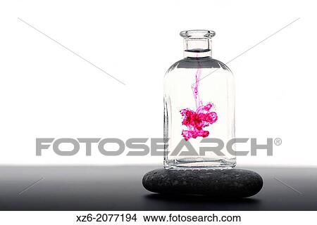 A drop of magenta liquid dissolving in a glass bottle with water. View Large Photo Image Picture - A drop of magenta liquid dissolving in a glass bottle with water.. Fotosearch