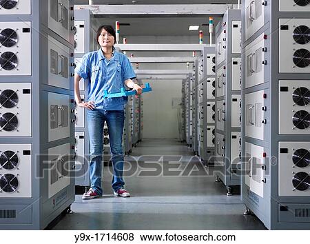 A employee of a Battery factory standing in a room of industrial-sized Li-ion battery chargers, where the batteries are brought for their intial charge View Large Photo Image Stock Photo - A employee of a Battery factory standing in a room of industrial-sized Li-ion battery chargers, where the batteries are brought for their intial charge. Fotosearch