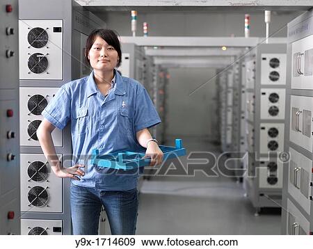 A employee of a Battery factory standing in a room of industrial-sized Li-ion battery chargers, where the batteries are brought for their intial charge View Large Photo Image Stock Photo - A employee of a Battery factory standing in a room of industrial-sized Li-ion battery chargers, where the batteries are brought for their intial charge. Fotosearch