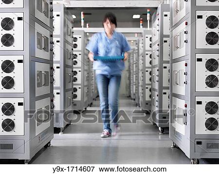 A employee of a Battery factory walking through a room of industrial-sized Li-ion battery chargers, where the batteries are brought for their intial charge View Large Photo Image Stock Photo - A employee of a Battery factory walking through a room of industrial-sized Li-ion battery chargers, where the batteries are brought for their intial charge. Fotosearch