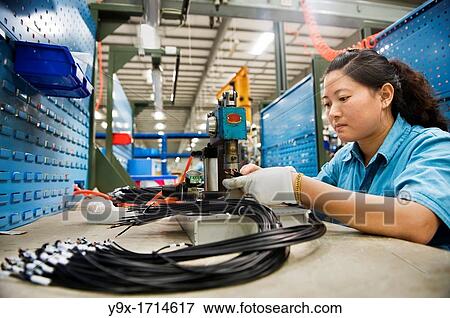 Stock Photo - A factory employee clamping and soding the smaller parts of the switchgears.. Fotosearch