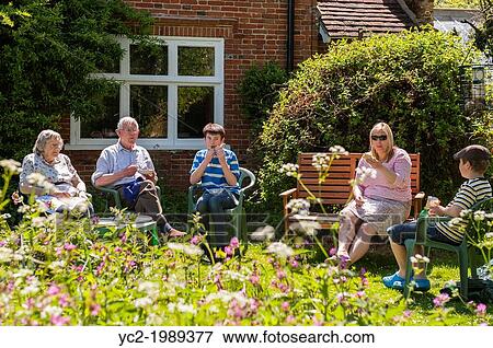 A family eating lunch outside in a cottage garden in summer in the Uk. View Large Photo Image Stock Photo - A family eating lunch outside in a cottage garden in summer in the Uk.. Fotosearch