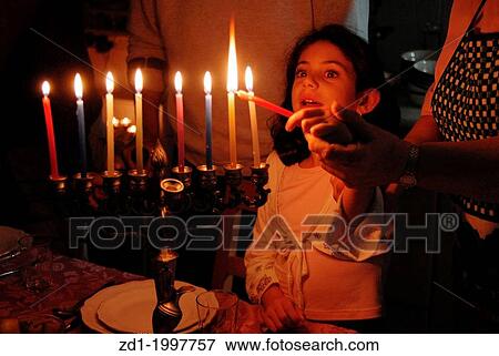 A family is lighting a candle for the Jewish holiday of Hanukkah. View Large Photo Image Stock Photo - A family is lighting a candle for the Jewish holiday of Hanukkah.. Fotosearch