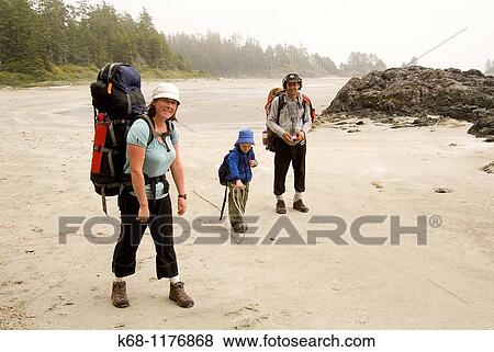 Stock Photo - A family of three hike together on the beach on Flores Island, Clayoquot Sound, BC, Canada. Fotosearch
