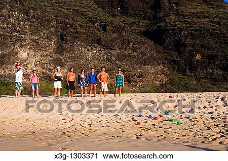 Stock Image - A family plays bocce ball alone an empty stretch of Polihale State Park beach, Kauai, Hawaii, USA. Fotosearch