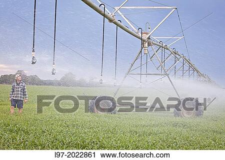 Stock Image - A farmer inspects his center pivot irrigation system, Victoria Australia.. Fotosearch