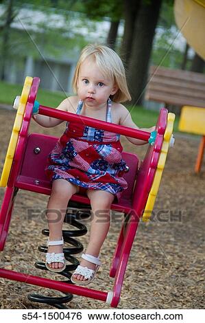 Stock Photograph - A female caucasian toddler, 1-2 years old, on a toy at the park in Spokane, Washington, USA.. Fotosearch
