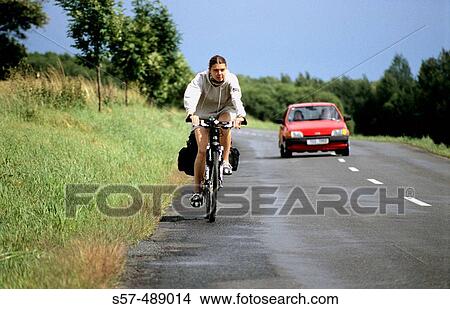A female cyclist rides her bicycle on a road View Large Photo Image Picture - A female cyclist rides her bicycle on a road. Fotosearch