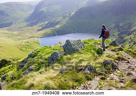 A female hiker walking down Long Stile towards Rough Crag with Blea Water in the distance in the Lake District. View Large Photo Image Stock Photo - A female hiker walking down Long Stile towards Rough Crag with Blea Water in the distance in the Lake District.. Fotosearch