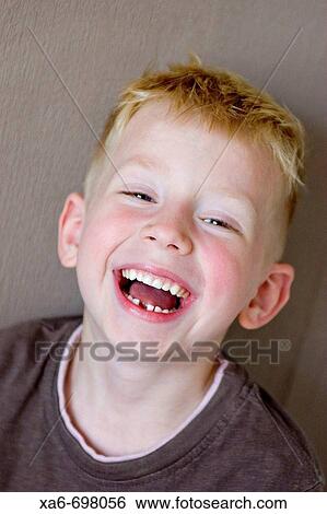 A five-year-old blonde, blue-eyed boy is laughing, showing a gap where he has lost a tooth. He is wearing a brown t-shirt and is standing in front of a brown wall. View Large Photo Image Stock Photograph - A five-year-old blonde, blue-eyed boy is laughing, showing a gap where he has lost a tooth. He is wearing a brown t-shirt and is standing in front of a brown wall.. Fotosearch