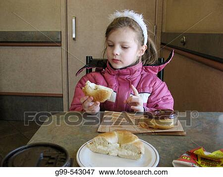 A four year old girl tries a cream cheese bagel in a restaurant in Windsor, Ontario, Canada. View Large Photo Image Stock Photo - A four year old girl tries a cream cheese bagel in a restaurant in Windsor, Ontario, Canada.. Fotosearch