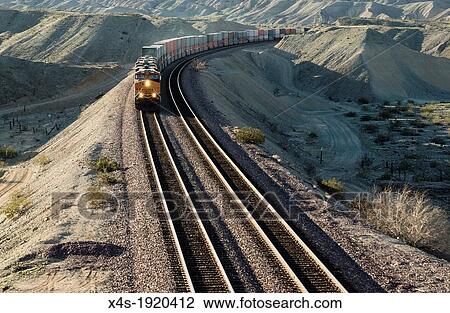A frieght train rounds a bend in the aride California desert in late afternoon View Large Photo Image Stock Image - A frieght train rounds a bend in the aride California desert in late afternoon. Fotosearch