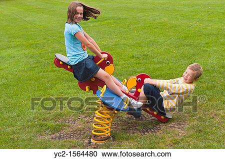 A girl and boy 10 and 8 play on a seesaw in a Uk park playground View Large Photo Image Stock Image - A girl and boy 10 and 8 play on a seesaw in a Uk park playground. Fotosearch