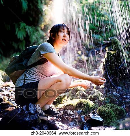 A girl with a backpack and hiking shoes holding her hands out under a waterfall off the Multnomah-Wahkeena Loop Trail in Oregon. View Large Photo Image Picture - A girl with a backpack and hiking shoes holding her hands out under a waterfall off the Multnomah-Wahkeena Loop Trail in Oregon.. Fotosearch