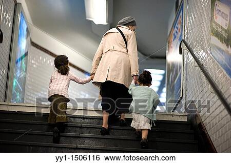 Stock Photograph - A grandmother climbs, with her two grandchildren, the stairs of a Paris subway- or metro-station.. Fotosearch