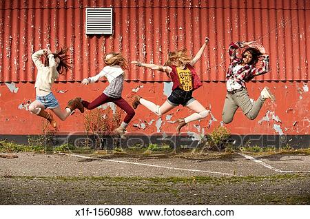 Stock Photo - A group of 13 year old teenage girls leaping in the air UK. Fotosearch