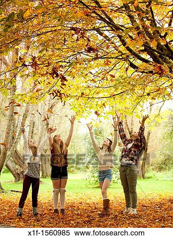 Stock Photography - A group of 13 year old teenage girls, throwing leaves into the air, autumn morning, UK. Fotosearch