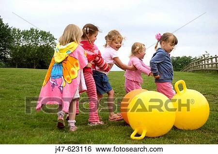 A group of 4, 5 year old girls holding on to each other in a line as they play round hoppers View Large Photo Image Stock Photograph - A group of 4, 5 year old girls holding on to each other in a line as they play round hoppers. Fotosearch