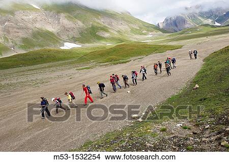 A group of hikers in line formation cross the plateau called Piano dei Camosci, Lepontine Alps Formazza Italy View Large Photo Image Picture - A group of hikers in line formation cross the plateau called Piano dei Camosci, Lepontine Alps Formazza Italy. Fotosearch
