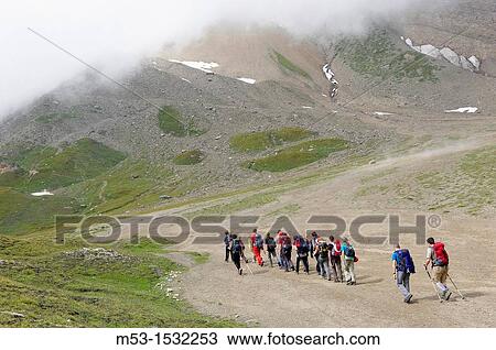 Stock Image - A group of hikers in single line formation cross the plateau called Piano dei Camosci, Lepontine Alps Formazza Italy. Fotosearch
