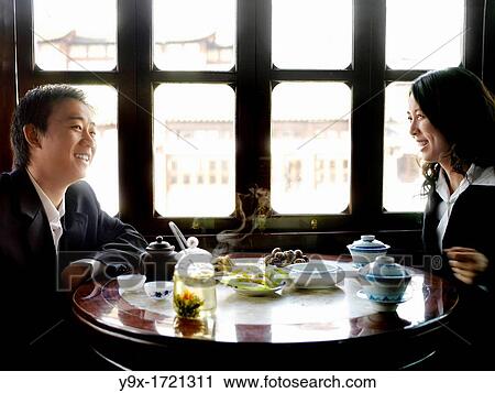 A happy Chinese business man and woman in suits sharing a laugh over a business lunch and tea in a traditional tea house View Large Photo Image Stock Image - A happy Chinese business man and woman in suits sharing a laugh over a business lunch and tea in a traditional tea house. Fotosearch