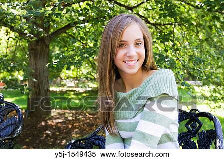 Stock Photography - A happy teenage girl sitting in garden on a sunny afternoon. Fotosearch