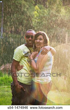 Stock Photograph - A happy, young, african-american couple playing in the rain. Fotosearch