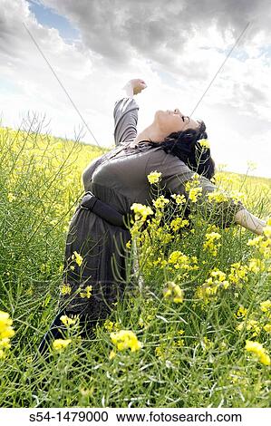 Stock Image - A happy young caucasian woman in a field of canola. Fotosearch