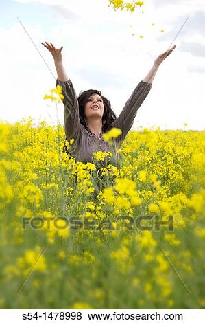 Stock Photo - A happy young caucasian woman in a field of canola. Fotosearch