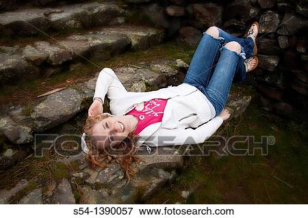 A happy young woman outdoors, lying on stone steps. View Large Photo Image Stock Photo - A happy young woman outdoors, lying on stone steps.. Fotosearch