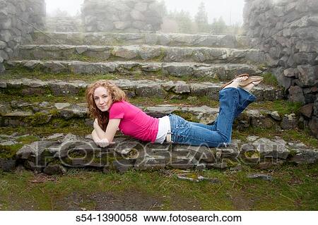 A happy young woman outdoors, lying on stone steps in the fog. View Large Photo Image Stock Photo - A happy young woman outdoors, lying on stone steps in the fog.. Fotosearch