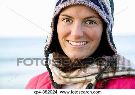A head and shoulders portrait of a young woman wearing a winter hat a scarf and a pink jacket. View Large Photo Image Picture - A head and shoulders portrait of a young woman wearing a winter hat a scarf and a pink jacket.. Fotosearch