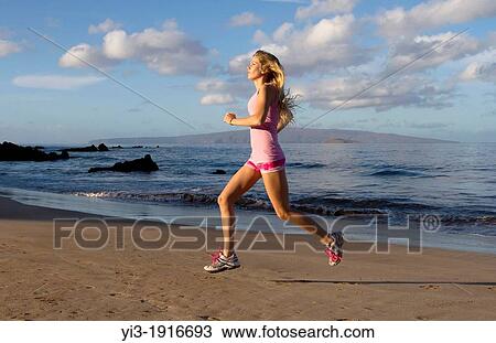 Stock Image - A healthy, fit woman exercises at the beach at Wailea, Maui, Hawaii. Fotosearch