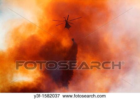 Stock Photo - A helicopter drops water on a mountain fire Table Mountain, Cape Town, South Africa. Fotosearch