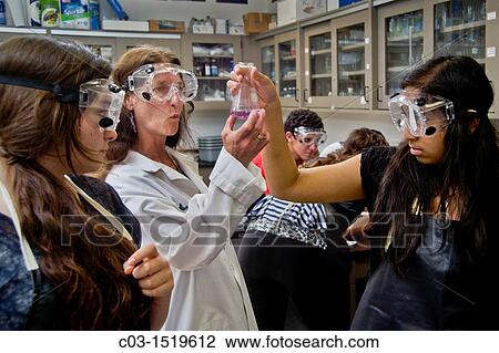 Stock Image - A high school chemistry teacher San Clemente, CA, inspects the results of her students? experiment using titration, a method of quantitative chemical analysis with the assistance of their teacher. Fotosearch