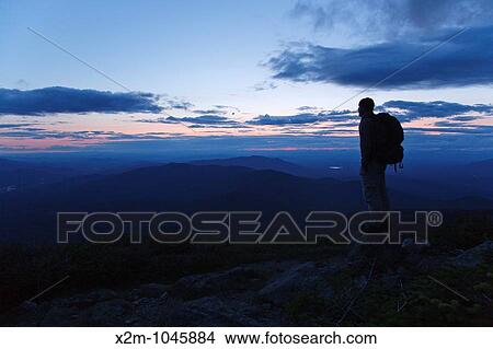 A hiker ascending the Jewell Trail enjoys the views at sunset Located in the White Mountains, New Hampshire USA View Large Photo Image Picture - A hiker ascending the Jewell Trail enjoys the views at sunset Located in the White Mountains, New Hampshire USA. Fotosearch