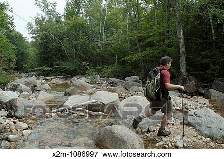 A hiker crosses Sawyer River on Hancock Notch Trail during the summer months Located in the White Mountains, New Hampshire USA View Large Photo Image Stock Photo - A hiker crosses Sawyer River on Hancock Notch Trail during the summer months Located in the White Mountains, New Hampshire USA. Fotosearch