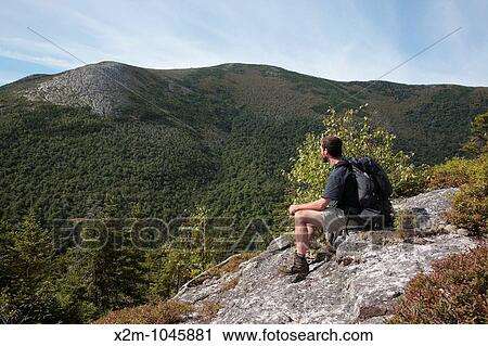 Stock Image - A hiker enjoys the view of the Baldface Range from Bicknell Ridge Trail during the summer months Located in the White Mountains, New Hampshire USA Charles Ravine is straight ahead. Fotosearch