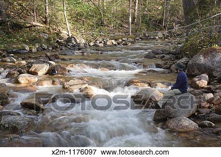 A hiker explores the Mad River which is on the side of Greeley Ponds Trail in the White Mountains, New Hampshire USA View Large Photo Image Stock Photo - A hiker explores the Mad River which is on the side of Greeley Ponds Trail in the White Mountains, New Hampshire USA. Fotosearch