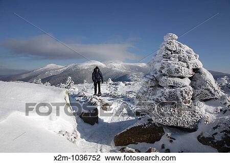 Stock Image - A hiker on the summit of Mount Pierce in the White Mountains, New Hampshire USA The Presidential Range can be seen in the background. Fotosearch