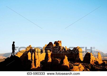A hiker stops to admire the last rays of light on sandstone fins and snowcovered La Sal mountains, Arches National Park, Utah. USA. View Large Photo Image Stock Image - A hiker stops to admire the last rays of light on sandstone fins and snowcovered La Sal mountains, Arches National Park, Utah. USA.. Fotosearch