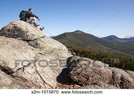 Stock Image - A hiker takes in the views from the summit of Mount Liberty during the summer months Located in the White Mountains, New Hampshire USA. Fotosearch